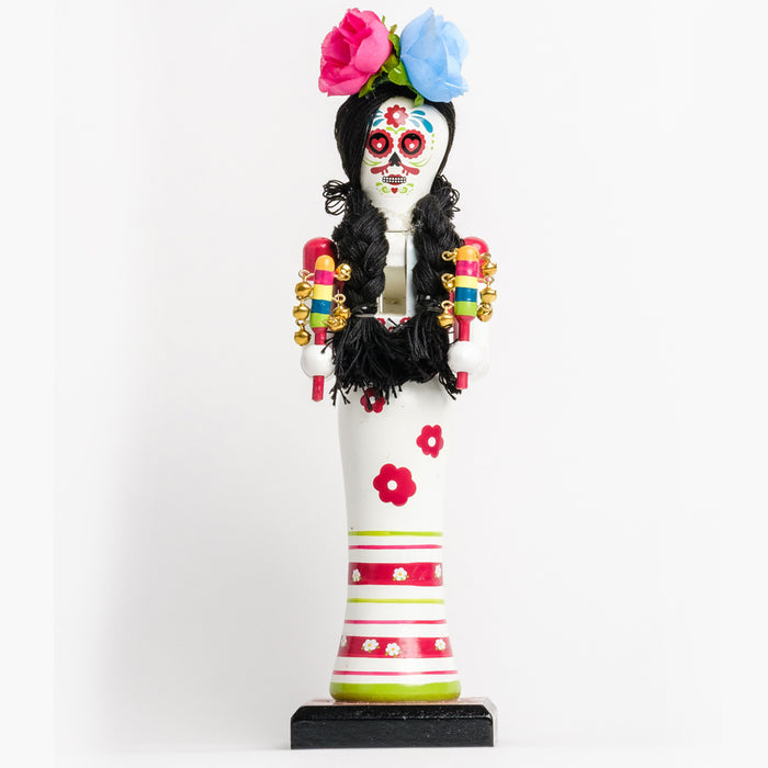 Día de los Muertos Bride holding bell sticks w/ a painted skull face in a white dress with pink & green flowers & stripes