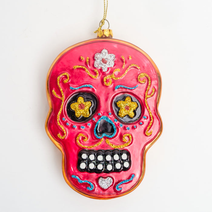 a red sugar skull ornament with a gold border, yellow floral eyes, a black nose, & gold, blue, & silver glitter accents