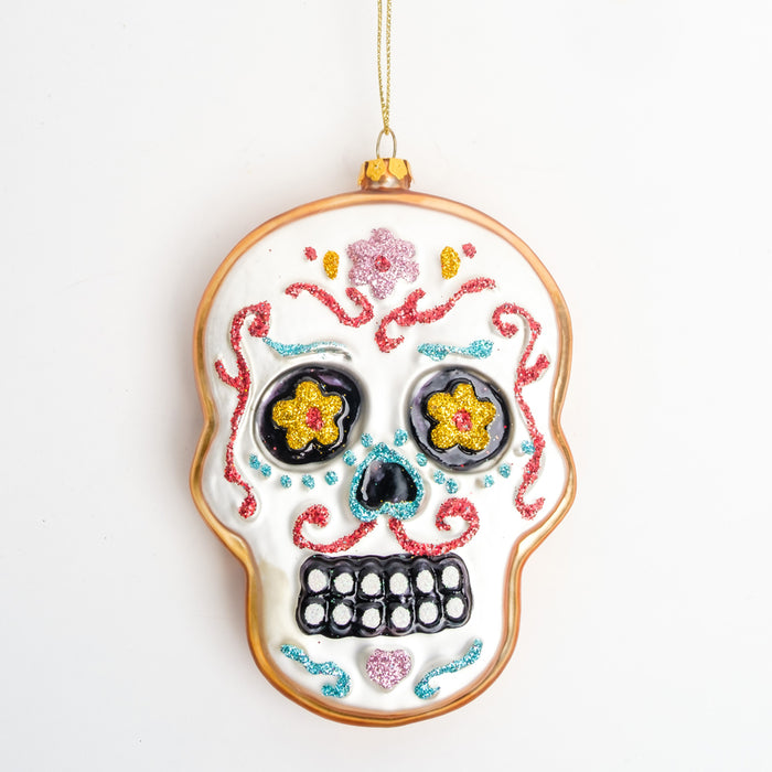 a white sugar skull ornament with a gold border, yellow floral eyes, a black nose, & red, turquoise, & pink glitter accents