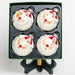a box set of 4 ball ornaments of Santa's face with a white glitter beard, a red gemstone nose, & a red and white striped hat