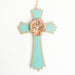 A wooden cross ornament in a faded light blue color with a bronze flower & a silver gemstone in the center