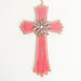 A wooden cross ornament in a faded red color with a bronze flower & a silver gemstone in the center